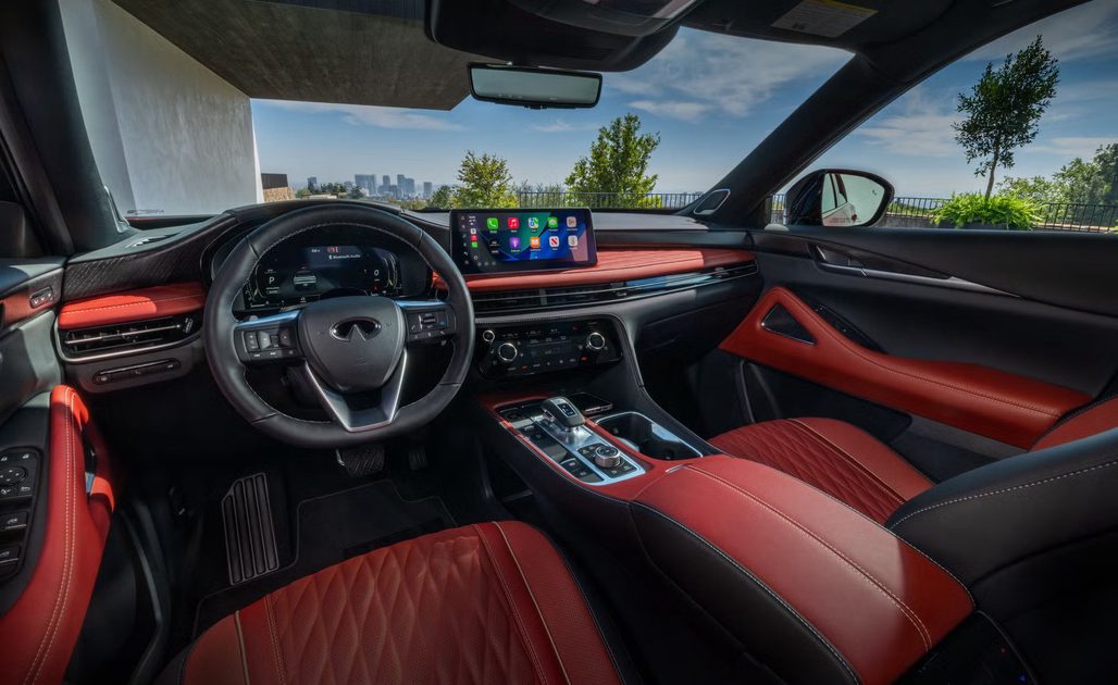 vehicle interior view red and black leather seats digital display center console with city skyline through windshield.