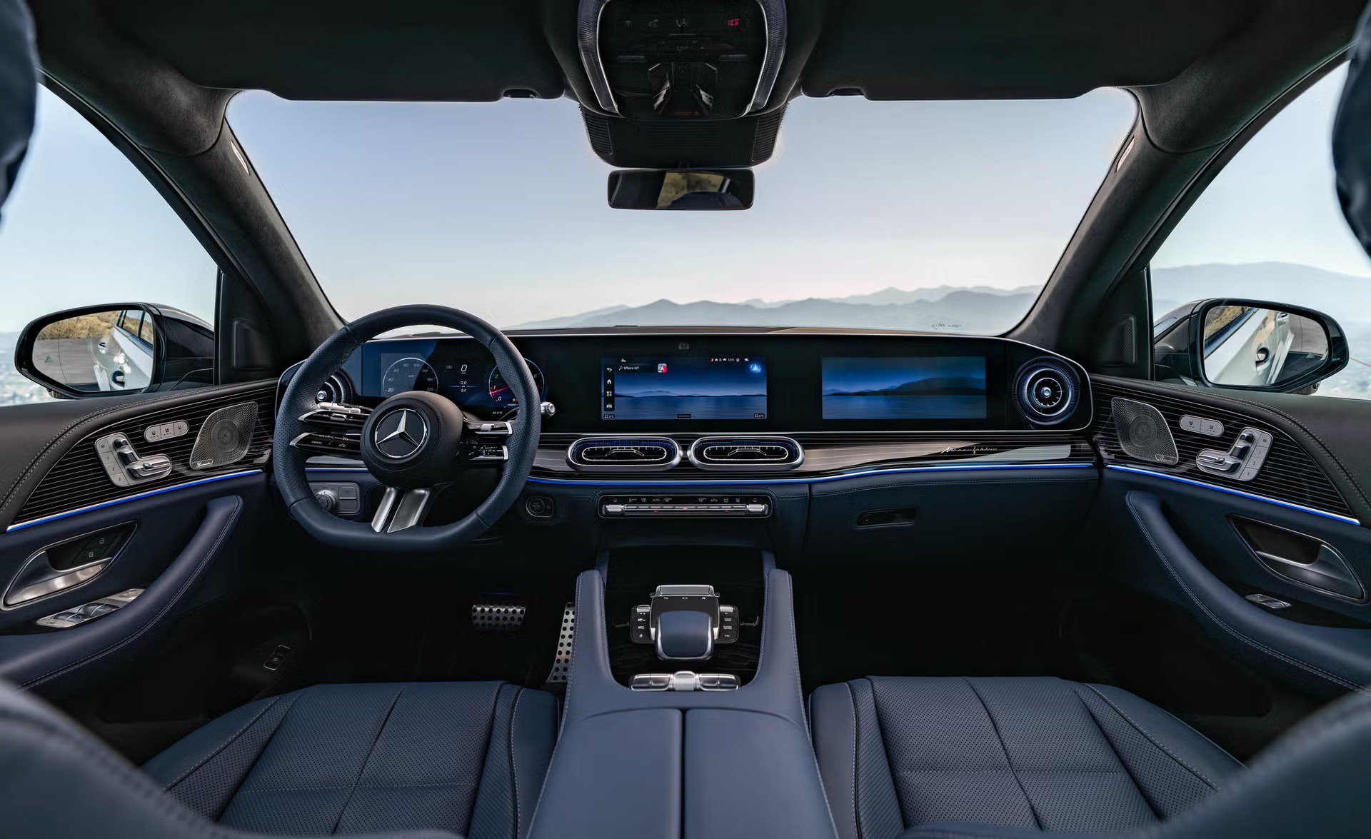 vehicle interior view, dual screens on dashboard, leather seats and ambient lighting, mountain horizon through windshield.